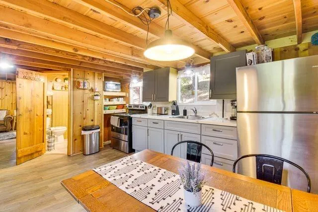 a kitchen with stainless steel appliances granite countertop a refrigerator a sink dishwasher a stove and white countertops with wooden floor