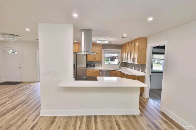 a large white kitchen with wooden floor and a large window