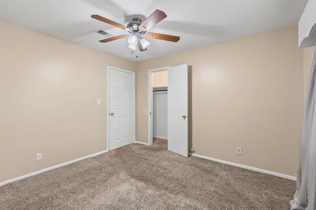 an empty room with a chandelier fan and a ceiling fan