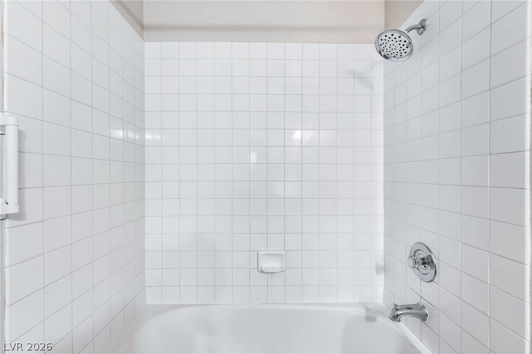 698 South Racetrack Road, Unit 1512 Henderson, NV 89015 - Photo 25 of 30 White square tile surrounds a classic built-in bathtub paired with chrome fixtures.