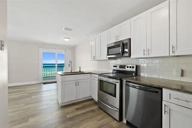 a kitchen with stainless steel appliances granite countertop a sink a stove a microwave and cabinets