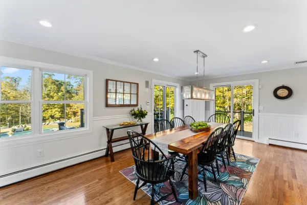 a view of a dining room and livingroom with furniture wooden floor a rug a potted plant and a chandelier