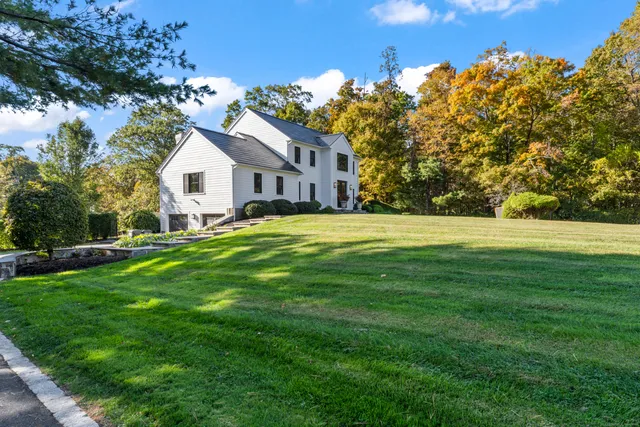 a front view of a house with a yard and trees
