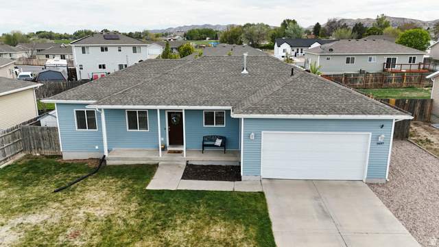 1437 925 South Vernal, UT 84078 - Photo 38 of 47 Ranch-style residence featuring light blue siding, a dark asphalt shingle roof, a two-car garage with a white door, a covered front porch, and a concrete driveway