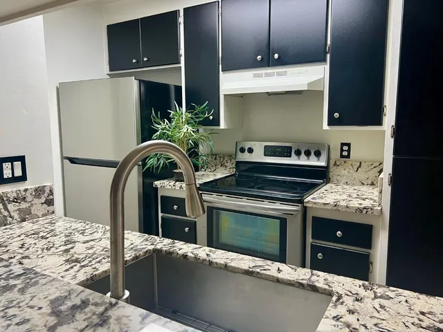 a kitchen with stainless steel appliances kitchen island granite countertop a stove a sink and a refrigerator