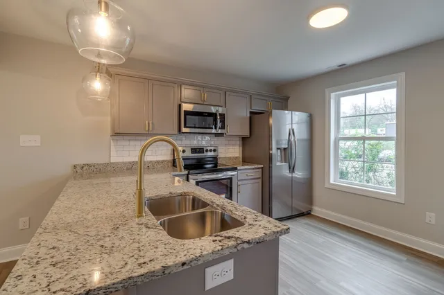 a kitchen with stainless steel appliances granite countertop a sink a stove and a refrigerator