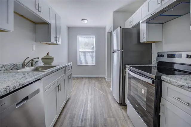 a kitchen with granite countertop a refrigerator stove and sink