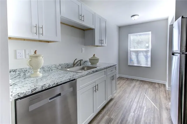 a kitchen with granite countertop white cabinets and a wooden floor