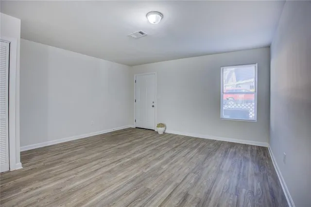 an empty room with wooden floor and windows
