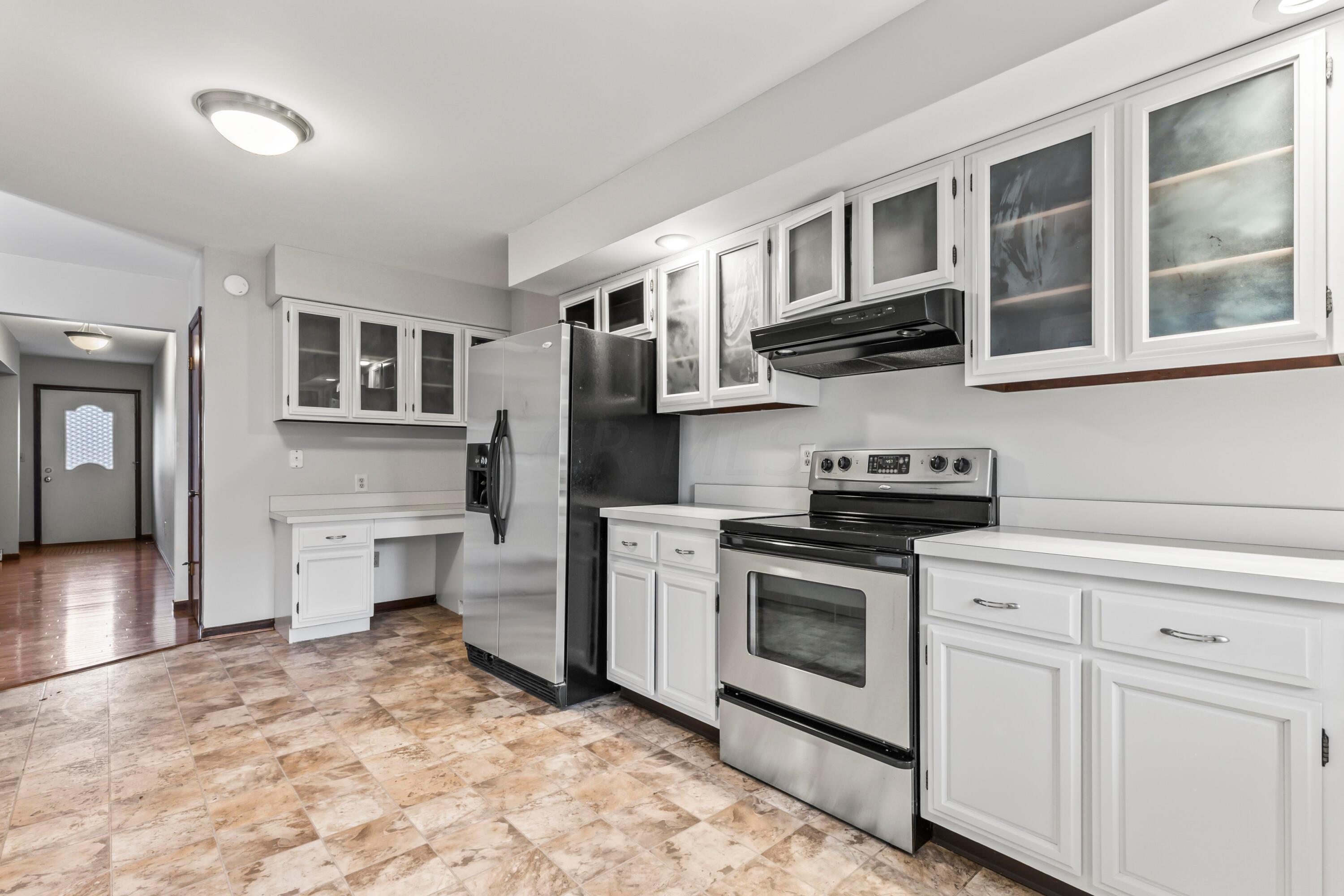 7020 Rieber Street Columbus, OH 43085 - Photo 12 of 40 • New neutral vinyl flooring ~ 2006 • Grey painted walls • Raised panel, white painted cabinets with glass fronts • New Whirlpool® refrigerator ~ 2017 • New Whirlpool® electric range ~ 2017 • Allure® rangehood • New Kenmore® dishwasher ~ 2017 • Double bowl, stainless steel sink with sprayer • New disposal • Can lighting • New sliding doors to screened porch • Planning desk • Buffet/media center • Pantry closet • Sliding doors to Screened Porch
