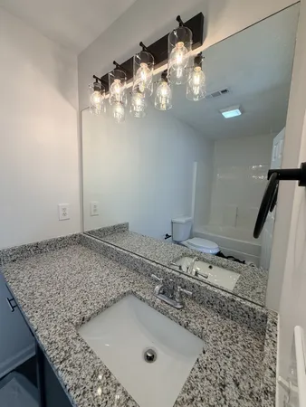 a bathroom with a granite countertop sink a mirror and shower