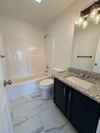 a bathroom with a granite countertop sink toilet mirror and bathtub