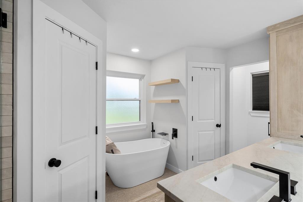 9346 Homestead Lane Forney, TX 75126 - Photo 15 of 39 Dual sinks, beautiful soaker tub, separate shower, and Leathered Taj Mahal countertops are showstoppers in this primary bathroom.
