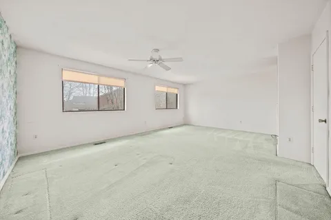 an empty room with windows and ceiling fan