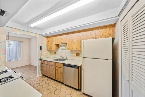 a kitchen with a sink a refrigerator and white cabinets