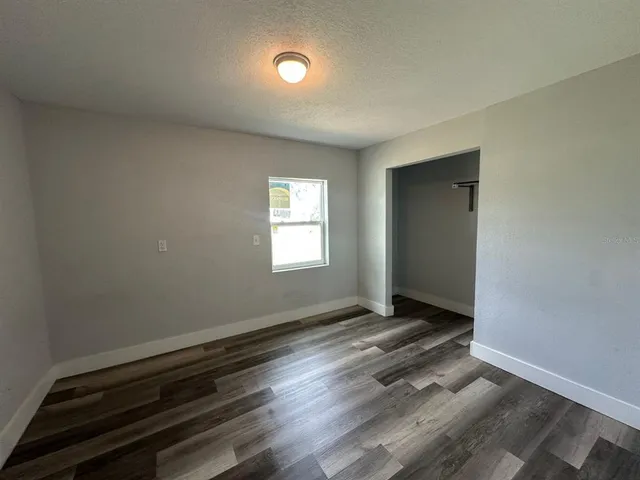 an empty room with wooden floor closet and windows