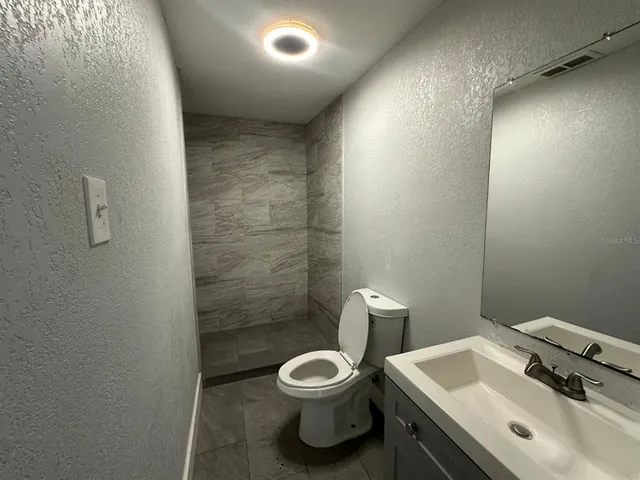 a bathroom with a sink a toilet and a mirror