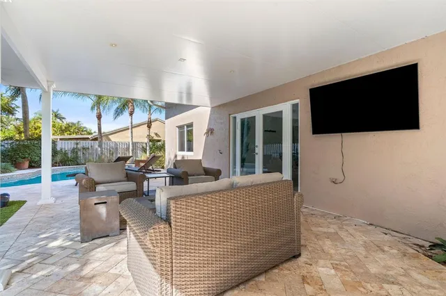 a living room with couches a flat screen tv and a floor to ceiling window