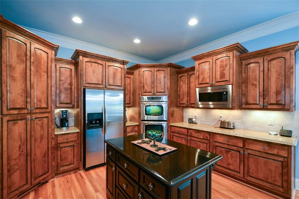 3435 Hidden Shoals Road Northeast Buford, GA 30519 - Photo 32 of 108 a kitchen with stainless steel appliances granite countertop a refrigerator a sink dishwasher a stove and wooden cabinets with wooden floor
