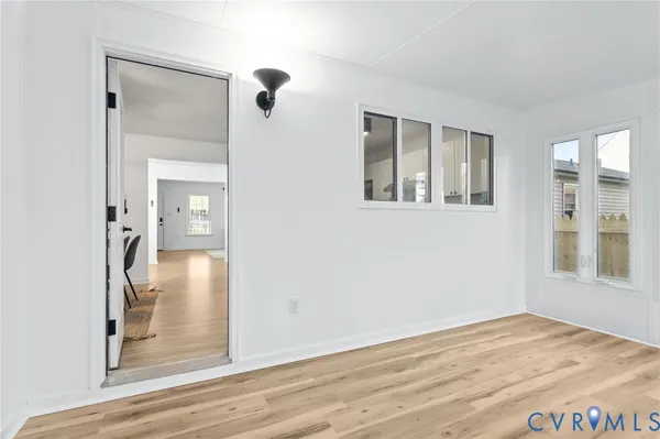 a view of a hallway with wooden floor and a bathroom