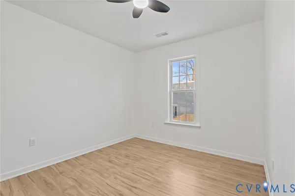 an empty room with a window and ceiling fan