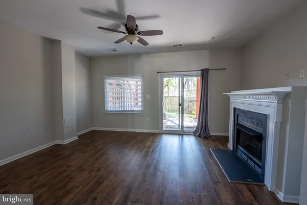 an empty room with wooden floor fireplace and windows