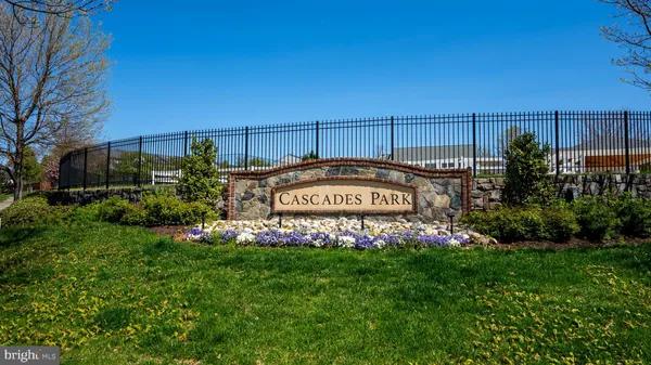 a view of a sign board with flower plants and wooden fence