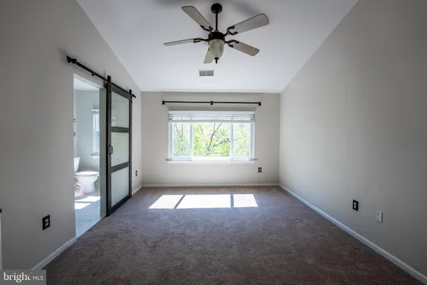 an empty room with windows and ceiling fan