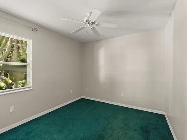 an empty room with a window and a fan