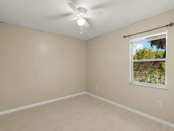 an empty room with a window and a fan