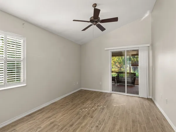 a view of empty room with wooden floor and fan