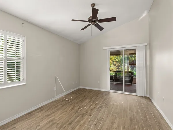 a view of empty room with wooden floor and fan