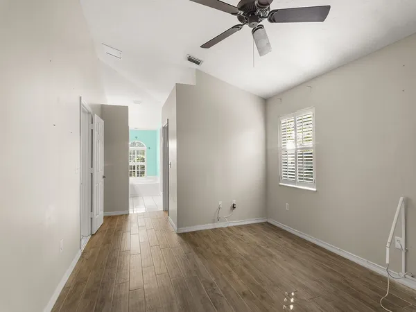 a view of an empty room with a window and wooden floor
