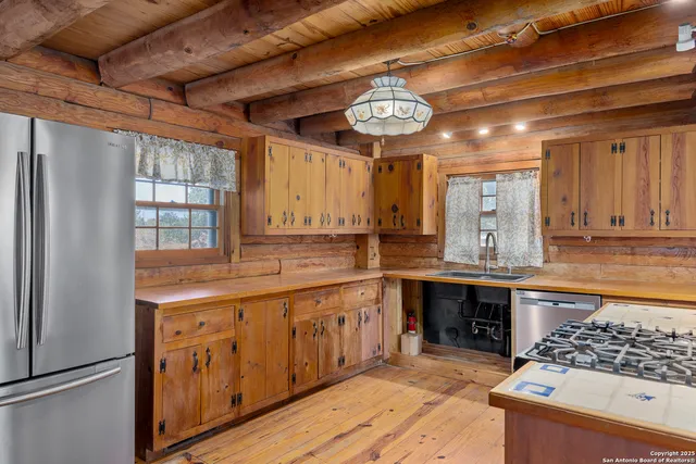 a large kitchen with a large counter space a sink stainless steel appliances and cabinets