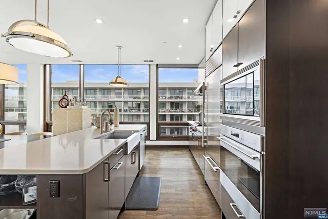 a kitchen with kitchen island a large counter top space a sink stainless steel appliances and cabinets
