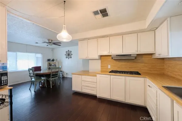 a kitchen with stainless steel appliances granite countertop a stove a refrigerator a kitchen island a dining table and chairs with wooden floor