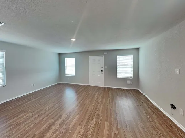 an empty room with wooden floor and window