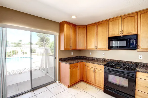 a kitchen with granite countertop a stove top oven microwave and cabinets