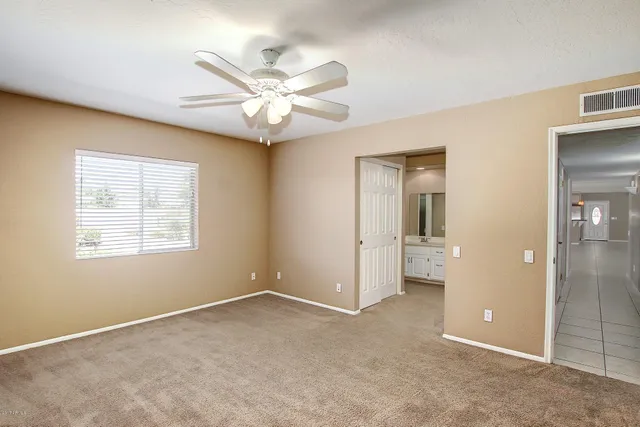 an empty room with closet and a chandelier fan
