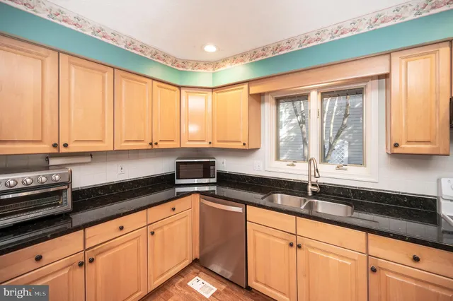 a kitchen with granite countertop a sink a window and cabinets