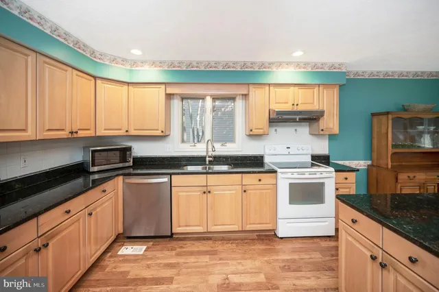 a kitchen with stainless steel appliances granite countertop a stove a sink and a microwave