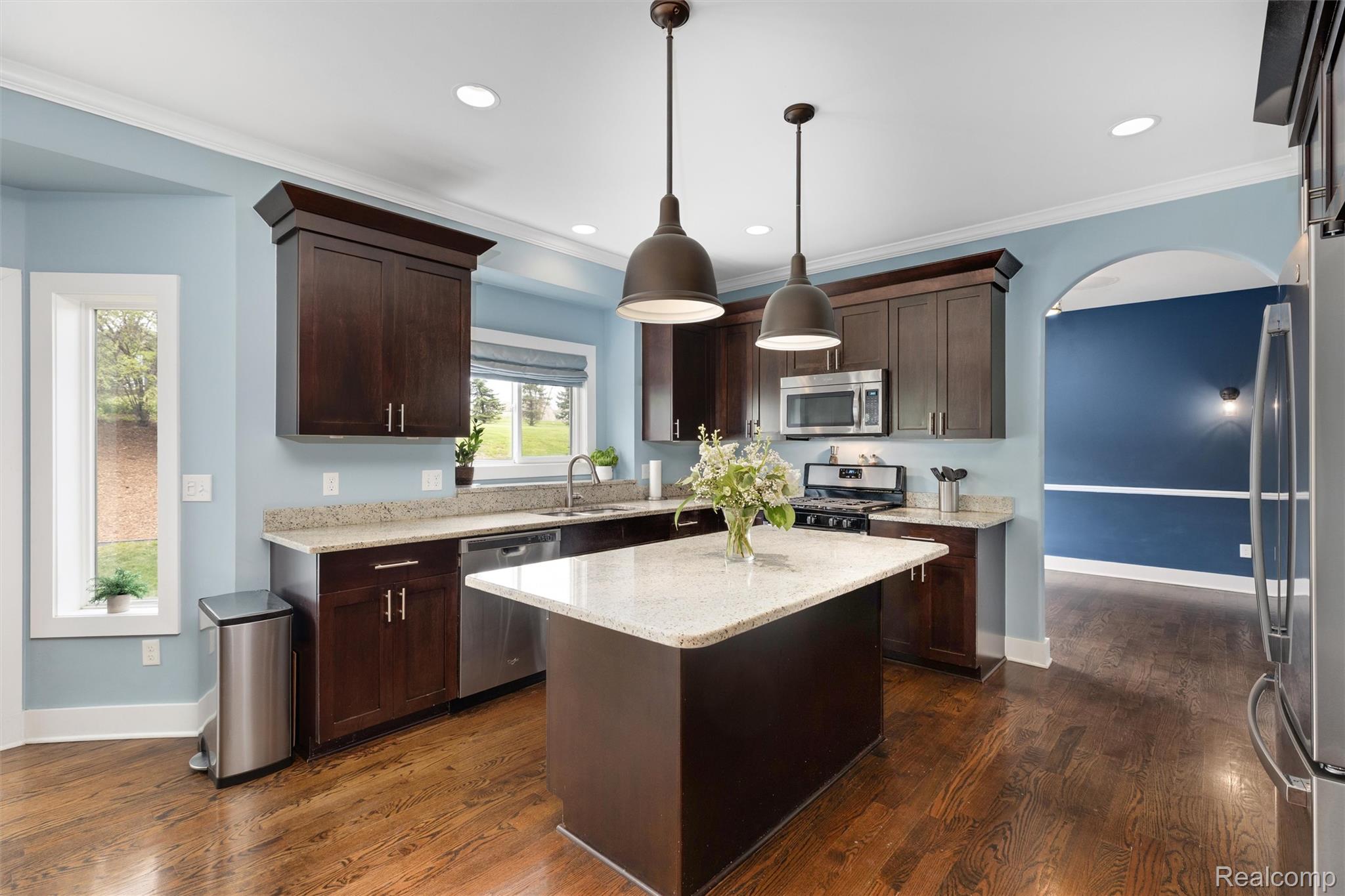 1016 West Snell Road Rochester, MI 48306 - Photo 13 of 35 Kitchen featuring a central island with a light-toned countertop, stainless steel appliances, dark wood cabinetry, and wood-finish flooring