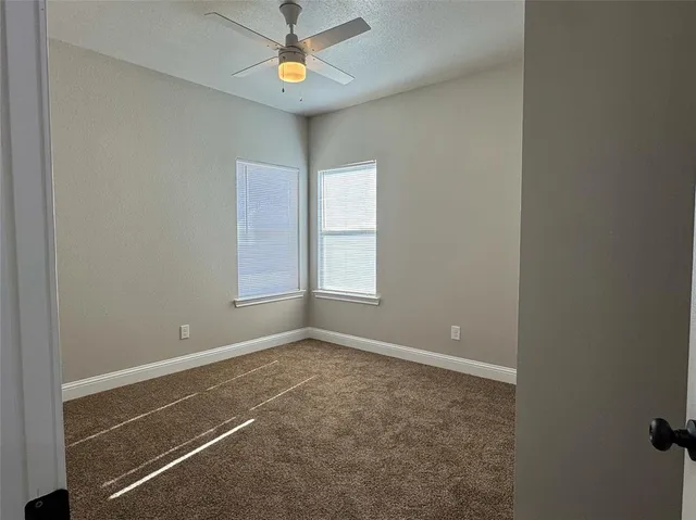 an empty room with windows and fan