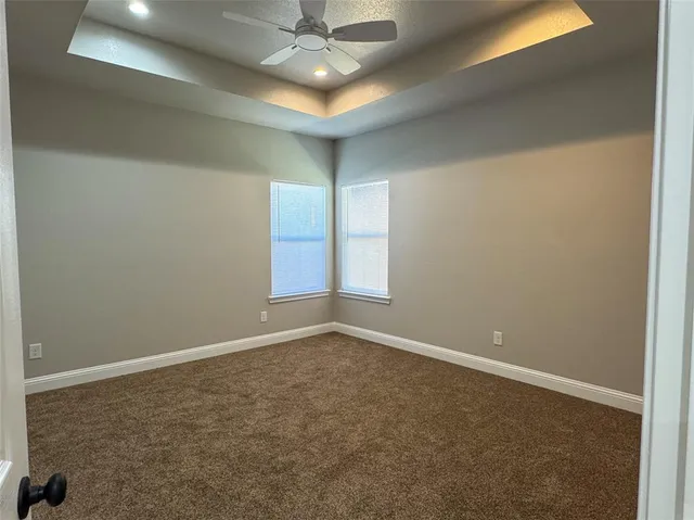 an empty room with a chandelier fan and windows