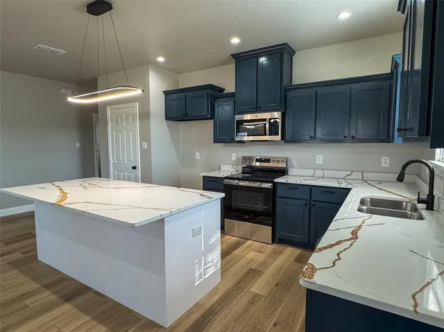 a kitchen with stainless steel appliances a sink a stove a refrigerator and cabinets