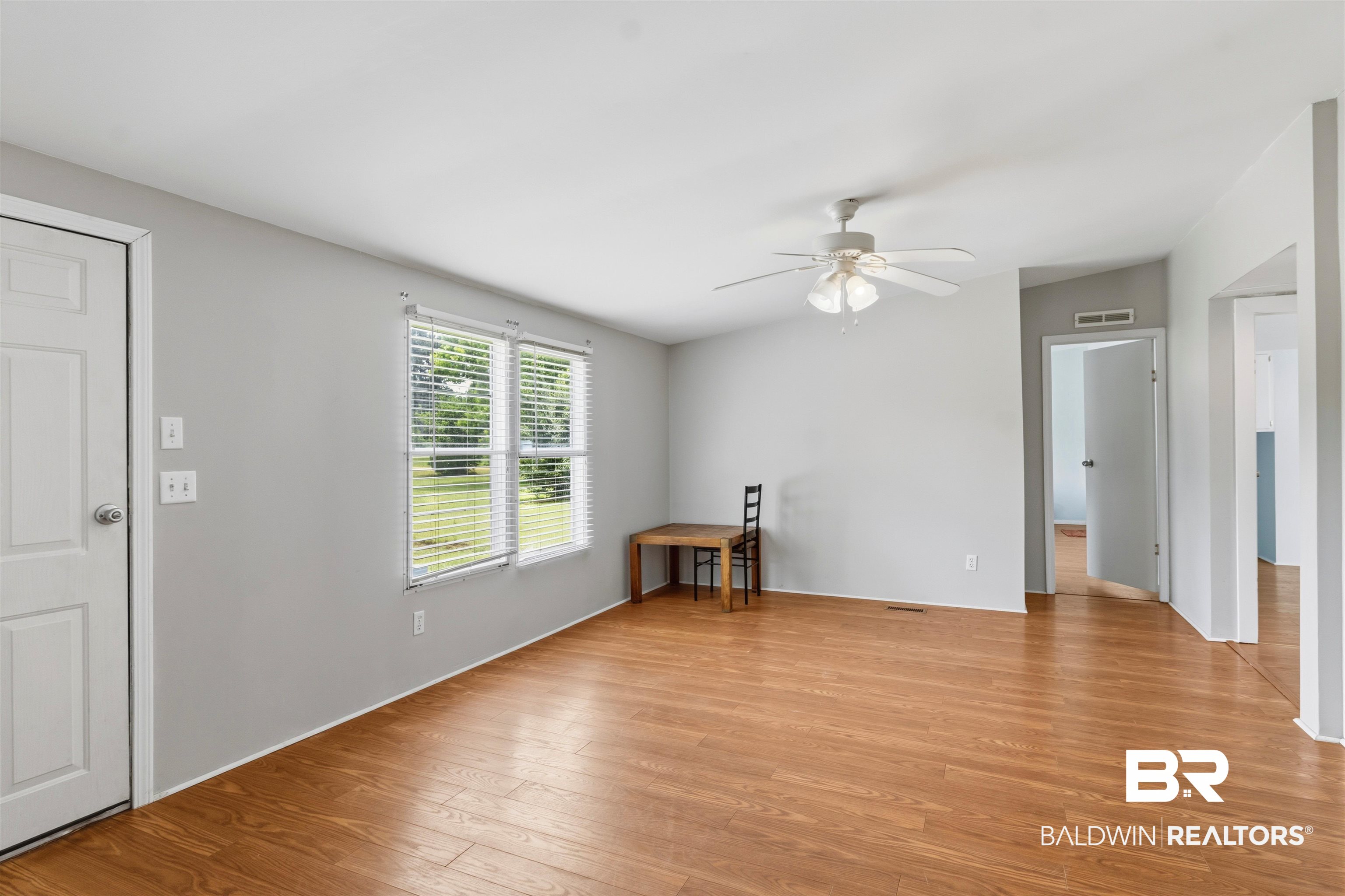 26788 Feely Road Elberta, AL 36530 - Photo 9 of 31 Spacious interior room featuring wood-finish flooring, two large windows with blinds, a ceiling fan with light fixture, and light gray wall paint