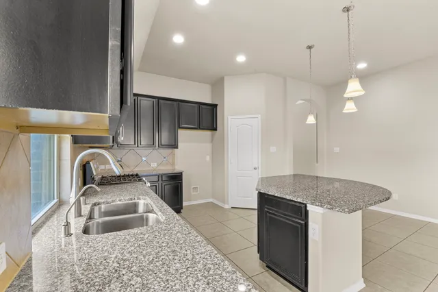 a large kitchen with kitchen island granite countertop a sink and a stove