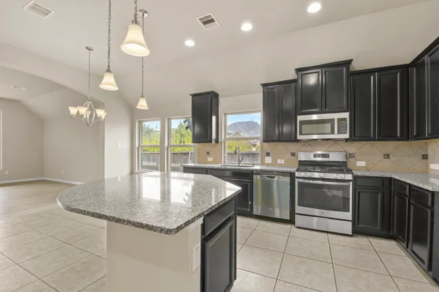 a kitchen with stainless steel appliances granite countertop a sink refrigerator and cabinets