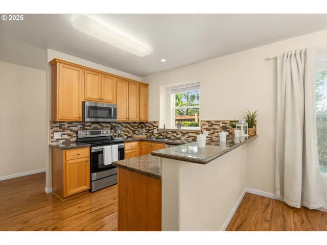 a kitchen with stainless steel appliances granite countertop a stove a sink and a microwave