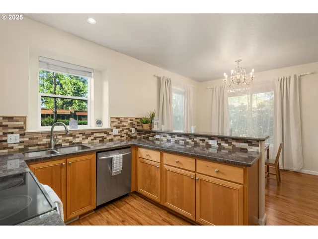 a kitchen with stainless steel appliances granite countertop a sink a stove a counter space and cabinets